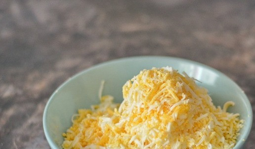 1. Этап. Классический еврейский салат из СССР: На мелкой тёрке натрите варёные яйца и плавленые сырки. Чтобы сырки лучше натирались, их можно подморозить 10-15 минут.