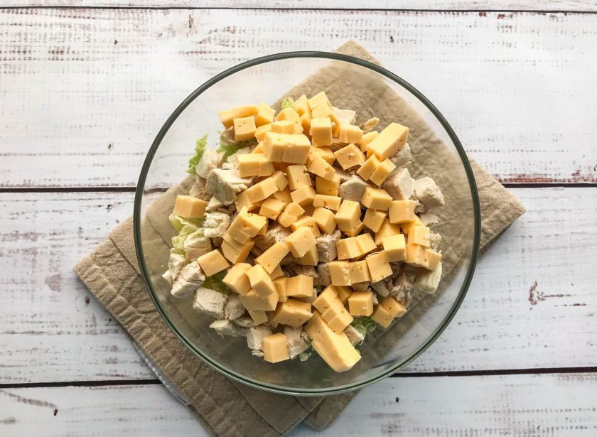 1. Этап. Пекинский салат с курицей и сухариками: Сыр нарежьте кубиками и выложите в тарелку.