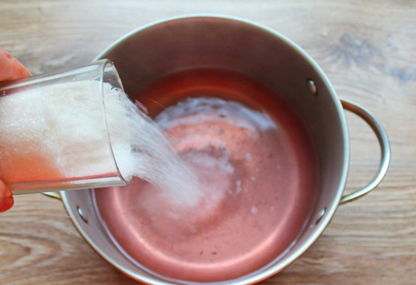 1. Этап. Компот из ранеток и черноплодки: Слейте воду из банки в кастрюлю и добавьте сахар. Перемешайте и поставьте на средний огонь. Доведите до кипения и варите до растворения сахара.