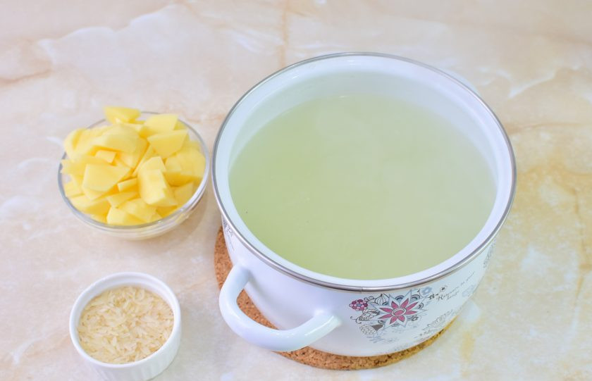 1. Этап. Рассольник с рисом и колбасой: Бульон доведите до кипения и отправьте в него нарезанный картофель и рис. Оставьте вариться минут на 12-15.