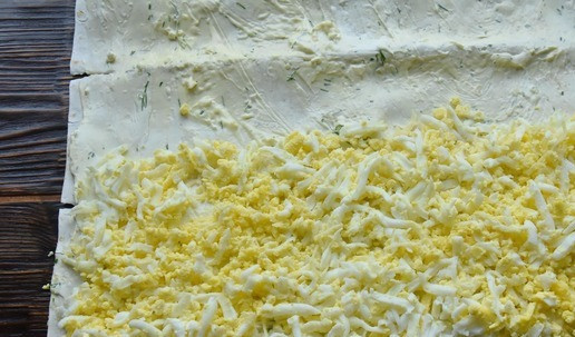 1. Этап. Тунец в лаваше: На лаваш рядами выкладываю продукты Первый ряд натертых на терке яиц. На край лаваша выкладываю плотнее к друг другу ряд маслин.