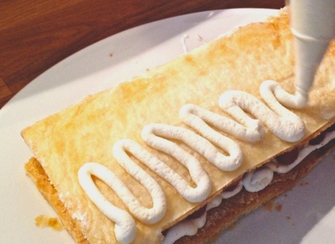 1. Этап. Мильфей со взбитыми сливками и малиной: 3. Достаньте противень и разрежьте тесто на 3 части. Выложите 1/3 части, смажьте кремом, выложите ягоды малины, накройте второй частью.