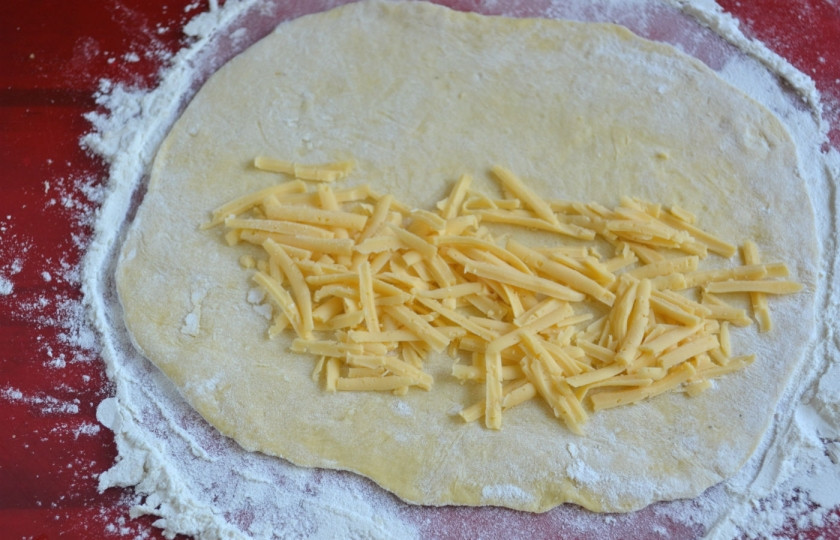 1. Этап. Чебуреки с сыром: Тесто разделите на 4-5 частей (в зависимости от того, какие чебуреки по размеру вы хотите получить). Раскатайте каждую часть в форме круга, условно поделите круг пополам, на одну половину положите тертый сыр.