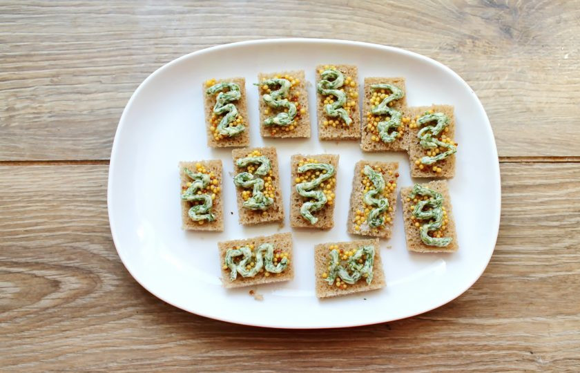 1. Этап. Канапе с селедкой и черным хлебом на шпажках: Укроп мелко порежьте и смешайте с мягким сливочным маслом. Нанесите при помощи корнетика полоски масла на горчицу. Или намажьте смесь на горчичный слой тонким слоем.