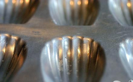 1. Этап. Мадлены: 1. Просеять вместе муку и разрыхлитель в миску. С помощью миксера взбить яйца и сахар вместе на высокой скорости, пока масса не станет светлее по цвету, от 2 до 4 минут. Добавить цедру лимона и ванильный экстракт. Аккуратно добавить смесь в муку и перемешать резиновым шпателем, затем добавить топленое масло. Накрыть тесто полиэтиленовой пленкой и поставить в холодильник по крайней мере на 3 часа или больше. Тесто может храниться в холодильнике до 2 дней. Разогреть духовку до 200 градусов и установить стойку в центре. Если ваша форма для мадленов не имеет антипригарного покрытия, хорошо смажьте ее маслом и слегка посыпьте мукой. Если форма силиконовая, ничего не надо делать.