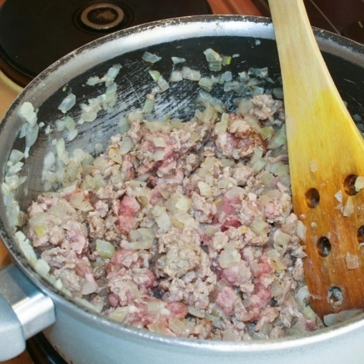 1. Этап. Мусака по-гречески: 2. Пока баклажаны подрумяниваются в духовке, начистите и нарежьте кубиками лук и чеснок. Затем обжарьте их до мягкости на масле в большой кастрюле. Как только лук станет мягким, добавьте фарш из баранины и обжарьте, помешивая, до полной готовности мяса.