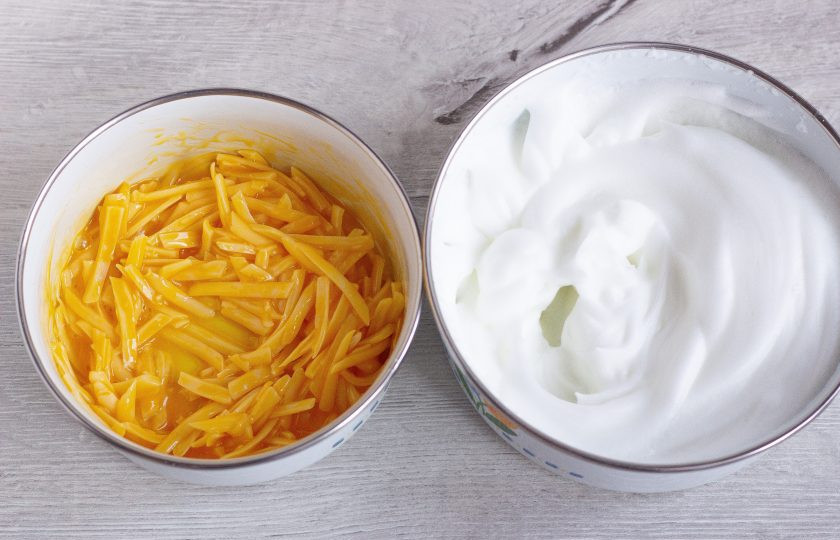 1. Этап. Кабачковое суфле под сырной шапкой: Сыр натрите на крупной терке. 1/3 отложите для верхней сырной корочки, остальное смешайте с желтками. Белки взбейте в крепкую пену.