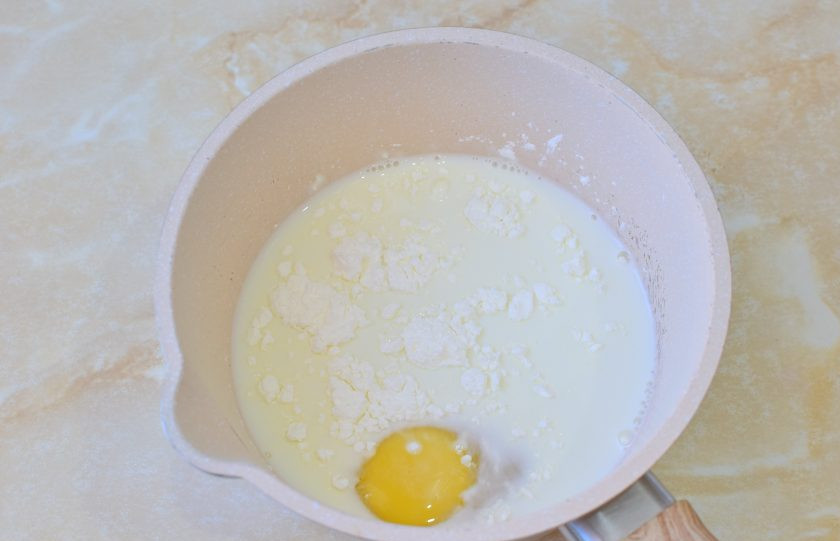 1. Этап. Меренговый рулет с заварным кремом: Первым делом необходимо приготовить крем, чтобы он успел остыть. Налейте в ковш молоко. Добавьте яйцо, сахар и крахмал. Все смешайте и поставьте на огонь.