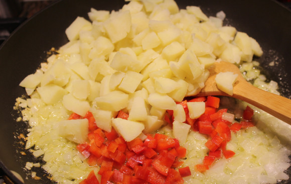 1. Этап. Говядина с помидорами и сыром: Растопите сливочное масло на сковороде. Обжарьте на нем мелко нарезанный лук. Добавьте нарезанный болгарский перец и картошку. Обжаривайте вместе несколько минут.