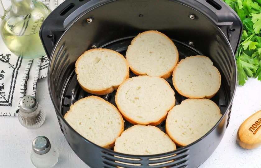 1. Этап. Брускетты в аэрогриле: В чашу аэрогриля выложите ломтики багета и сбрызните их растительным маслом. Активируйте технику на 5-6 минут при температуре 160 градусов.