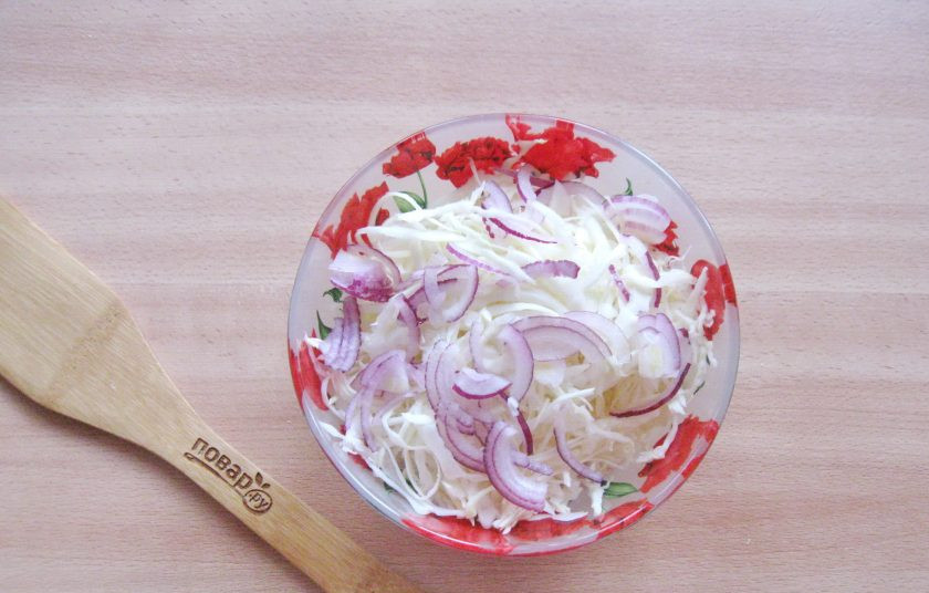 1. Этап. Капустный салат по-немецки: Репчатый лук очистите, помойте и нарежьте произвольно. Добавьте в капусту.