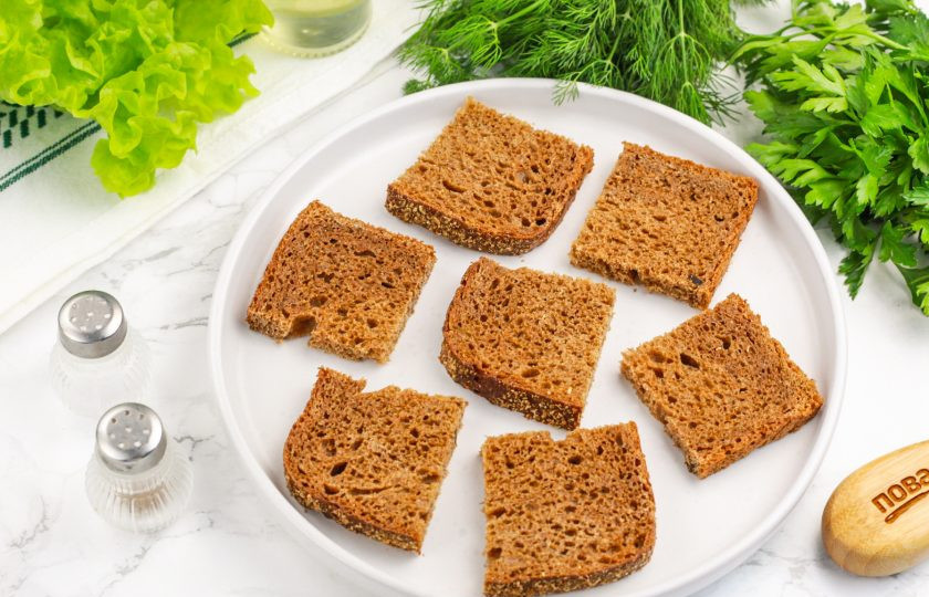 1. Этап. Канапе со шпротой: Ломтики бородинского или ржаного хлеба нарежьте на части, чтобы получились ровные квадраты или прямоугольники. Выложите их на тарелку или блюдо.