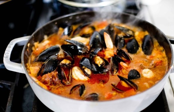 1. Этап. Жаркое с рыбой и морепродуктами в томатном соусе: 3. Выложите в кастрюлю нарезанный кубиками помидор, рыбу и морепродукты. Добавьте по вкусу соль и перец. Томите на среднем огне около 10-15 минут до готовности.