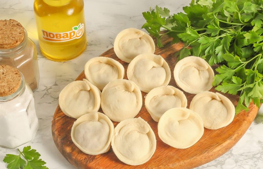 1. Этап. Пельмени Бульмени: Залепите края и затем соедините каждый край друг с другом, получая аппетитные заготовки. Подпылите доску или тарелку мукой и выложите на нее заготовки. Отправьте их в морозильную камеру на 1 час, чтобы они как следует подморозились.