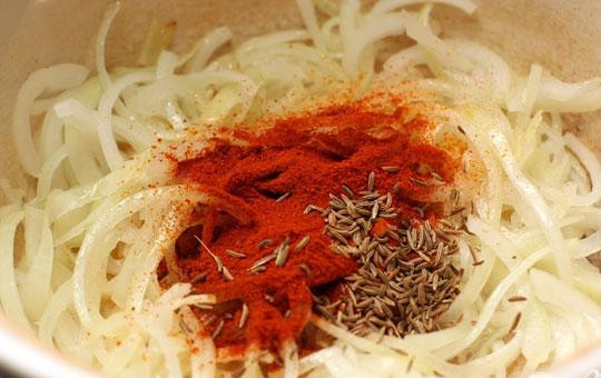 1. Этап. Гуляш из свиной шейки: 1. Тонкими полукольцами нарезаем лук и спассирум его в кастрюле, где будем готовить гуляш (дно кастрюли должно быть толстым). На среднем огне готовим 2-3 минуты. Лук должен стать полупрозрачным. Добавляем специи и пару минут готовим еще, помешивая для того, чтобы хорошо смешались масло и паприка.