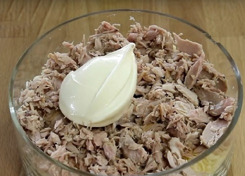 1. Этап. Салат из тунца и яиц: Сливаем жидкость с тунца, а саму рыбу измельчаем. Выкладываем ровным слоем и смазываем майонезом.