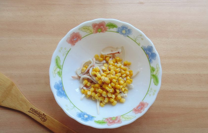 1. Этап. Салат с кальмарами и перепелиными яйцами: Добавьте консервированную кукурузу в салат.