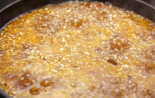 1. Этап. Плов на сковороде: Выкладываем в сковородку рис и аккуратно разравниваем его по всей поверхности, жидкость должна полностью накрывать рис. На среднем огне готовим рис в течение 10-15 минут. Если по истечении времени жидкость будет оставаться слишком много, то необходимо сделать сквозные дырочки в рисе.