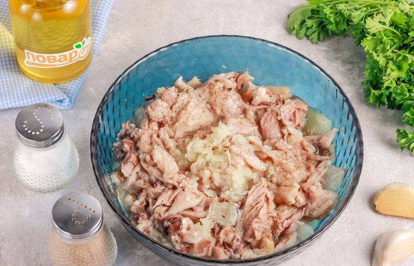 1. Этап. Холодец по-деревенски: Аккуратно извлеките ножки из бульона и процедите сам бульон через ситечко. Разделите мясо на части руками или нарежьте ножом. Очистите оставшиеся зубчики чеснока и спрессуйте их в мясо. Слегка посолите и поперчите, перемешайте.