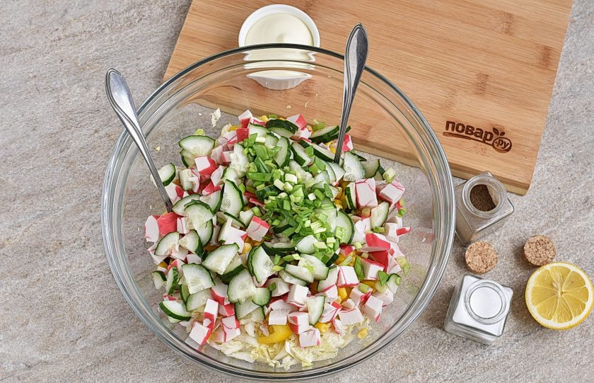 1. Этап. Крабовый салат с пекинской капустой: Огурец нарежьте кубиками, половину зеленого лука нашинкуйте и добавьте все в миску.