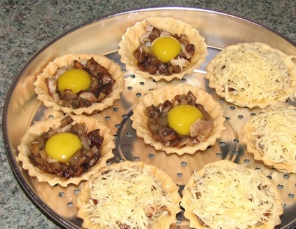 1. Этап. Тарталетки запеченные с начинкой: 4. Натрите на средней терке сыр. Дополнить закуску можно яйцом, которое аккуратно вбивается сверху начинки. Затем все засыпаете сыром и можно отправить готовиться тарталетки запеченные с начинкой в домашних условиях.