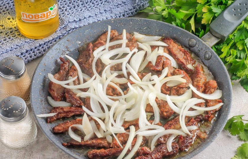 1. Этап. Соломка из говядины с репчатым луком: Нарежьте лук тонкими полукольцами. Переверните мясную нарезку на другую сторону с помощью силиконовой лопатки. Добавьте на сковороду нарезку лука и обжарьте все вместе еще 3-4 минуты.