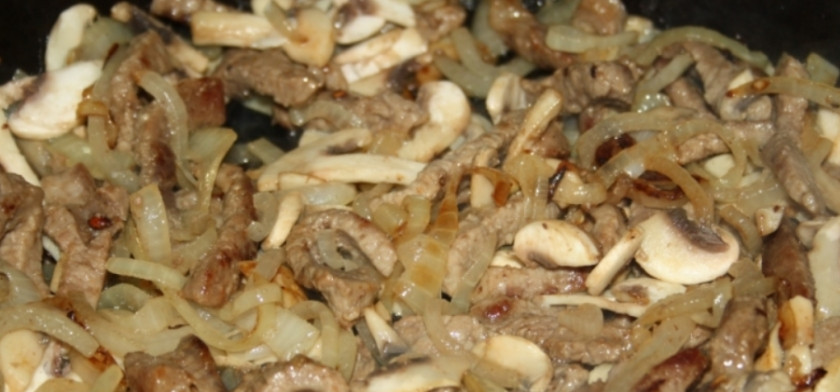 1. Этап. Бефстроганов с шампиньонами: Затем добавляем лук порезанный полукольцами и измельченный чеснок. Жарим до румяности. Добавляем шампиньоны, порезанные тонкими пластинками. Готовим еще 3-4 минуты.