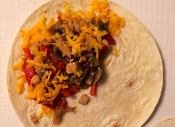 1. Этап. Кесадилья с курицей и грибами: Лепешку посыпьте тертым сыром, выложите начинку, только не перестарайтесь – лепешка должна закрываться свободно и начинка впоследствии не должна высыпаться. Сверху начинки насыпьте еще сыра, и согните лепешку пополам, закрыв её.