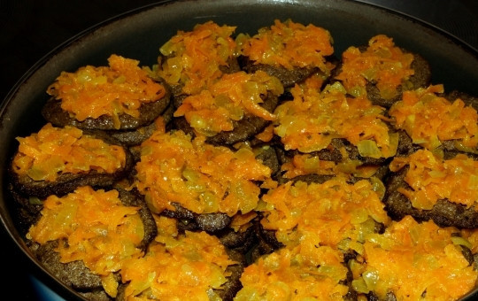 1. Этап. Печеночные оладьи из свиной печени: Готовые оладьи перекладываем в другую посуду с высокими бортами. Складываем слоями, а между оладками выкладываем пассированный лук с морковью.