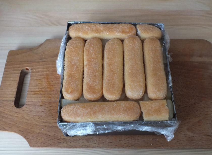 1. Этап. Торт из печенья савоярди: На ананасы уложите слой печенья савоярди, слегка пропитайте соком ананаса.