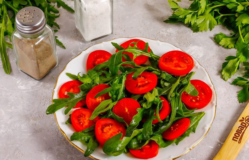 1. Этап. Салат с уткой и рукколой: Помидоры промойте в воде, вырежьте из них зеленые сердцевинки и нарежьте кружочками. Выложите между листьев рукколы.