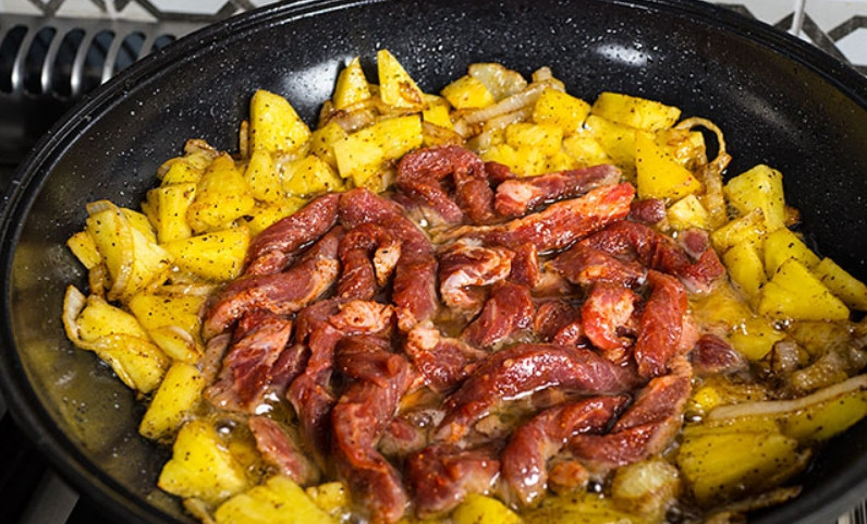 1. Этап. Плов в духовке со свининой: Самое время добавить свинину. Перемешайте и жарьте пока мясо не побелеет.