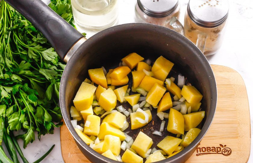 1. Этап. Чечевичный суп на кокосовом молоке: Очистите картофель и лук от кожуры, промойте в воде. Нарежьте луковицу мелкими кубиками, а картофель — средними. Прогрейте в казане, ковше или в кастрюле с антипригарным дном растительное масло. Выложите в него овощные нарезки и отпассейруте примерно 2-3 минуты до румяности.