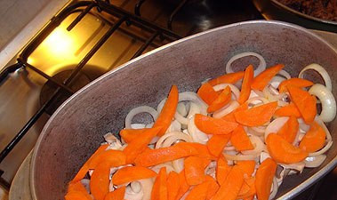 1. Этап. Тушеное мясо с грибами: 4. В конце жарки добавляем грибы и жарим еще пару минут на слабом огне. На дно казана выкладываем нарезанные лук и морковь, лавровый лист и перец горошком. Сверху выкладываем мясо с грибами. Заливаем водой и ставим тушиться.