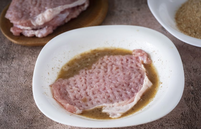 1. Этап. Котлеты отбивные из свинины: Выложите в яичную смесь одну отбитую котлету и окуните со всех сторон.