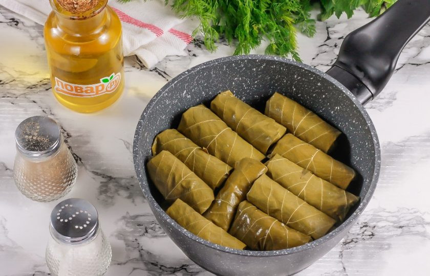 1. Этап. Долма с мятным соусом: Выложите на дно казана или ковша с антипригарным дном пару виноградных листьев, на них — приготовленную долму. Залейте горячей водой, чтобы она слегка покрывала долму. Накройте блюдцем, чтобы ни одна заготовка не развернулась. Отварите на умеренном нагреве примерно 20-25 минут. Чем мельче заготовки, тем меньше времени потребуется для их приготовления.