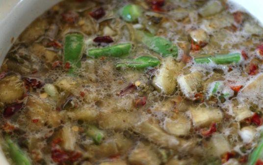 1. Этап. Суп из баклажанов: Уменьшить огонь и накрыть кастрюлю крышкой. Потушить так несколько минут. Масса должна заметно уменьшиться. Затем овощи залить водой или бульоном, поперчить и добавить лавровый лист (солить следует в конце). Далее добавить стручковую фасоль нарезанную на несколько частей.