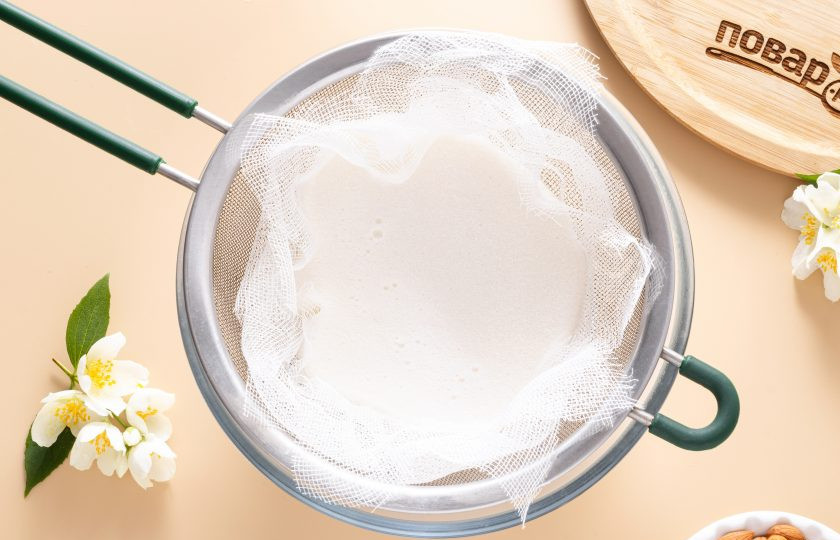 1. Этап. Абрикосовое молоко: Застелите мелкое сито несколькими солями марли и процедите получившуюся жидкость. Хорошенько отожмите жмых от абрикосовой косточки.