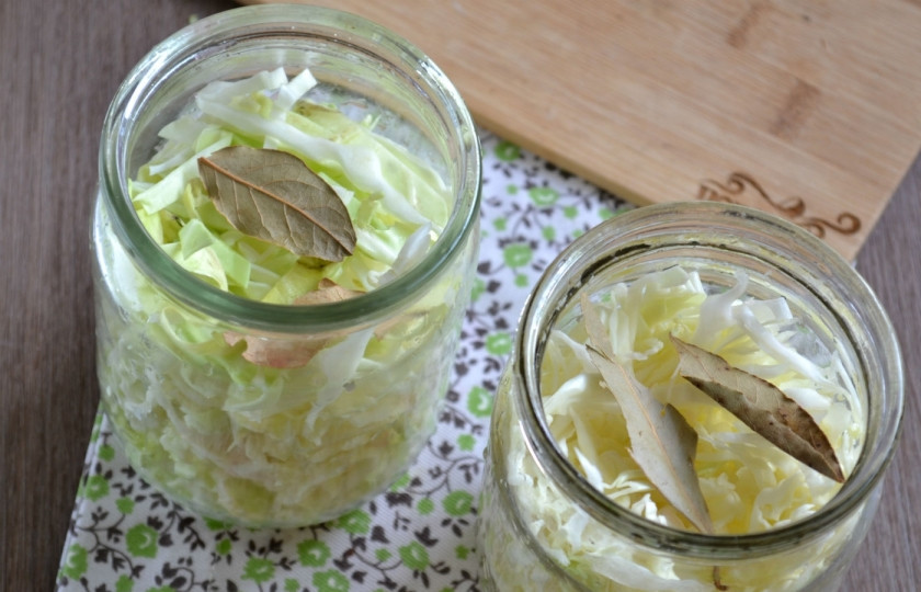 1. Этап. Капуста, маринованная со свеклой в банке: В чистые, желательно — стерилизованные банки (у меня объемом 0,5 литра) сложите капусту, хорошенько утрамбуйте её рукой. Потом в каждую банку положите по два лавровых листа.