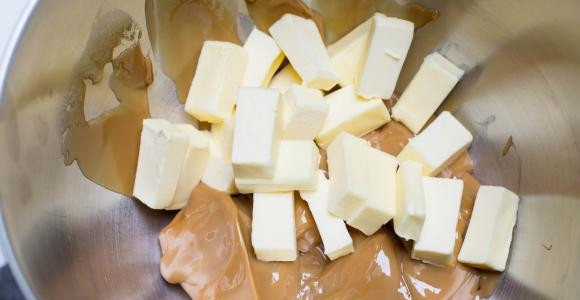 1. Этап. Торт Муравейник со сгущенкой: 6. Оставшееся сливочное масло нарежьте кусочками и выложите в миску, к нему добавьте вареное сгущенное молоко.