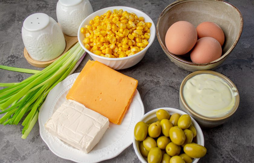 1. Этап. Салат Початок кукурузы: Подготовьте все необходимые ингредиенты для салата. Консервированную кукурузу откиньте на сито и дайте стечь всей жидкости. Сыр можно использовать только твердый или полутвердый, по вашим предпочтениям. Если вы используете свежую кукурузу, отварите её до готовности, а затем срежьте зёрна с початков.