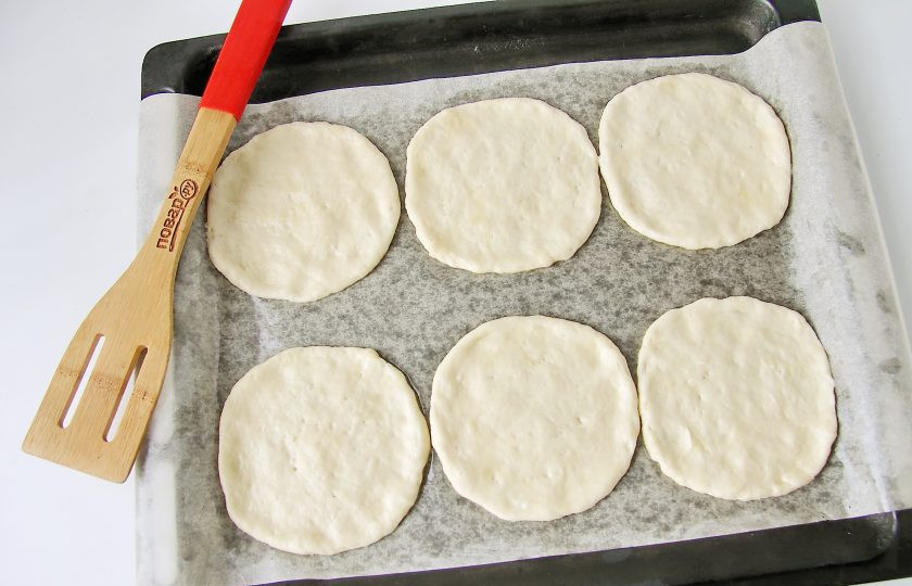 1. Этап. Мини пицца: Смажьте руки растительным маслом, сформируйте из теста шарики, переложите их на противень и расплющите руками в лепешку. Противень предварительно застелите пергаментом и смажьте маслом.