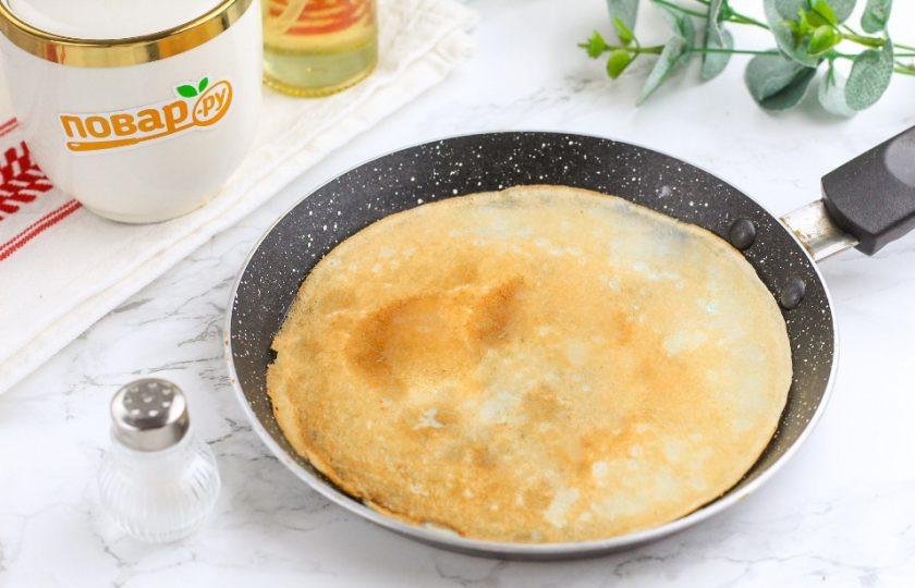 1. Этап. Блинный пирог с творогом: Спустя указанное время прогрейте сковороду на плите и смажьте ее растительным или сливочным маслом в первый раз, потом не нужно будет смазывать, так как жир присутствует в тесте. Обязательно перемешайте блинное тесто, поднимая муку со дна емкости. Влейте часть на раскаленную сковороду и обжарьте блин с одной стороны 1 минуту. Затем переверните и обжарьте еще 1 минуту.