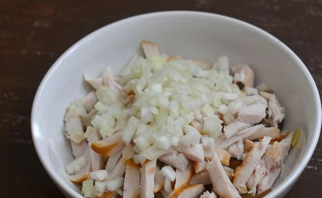 1. Этап. Салат с грудкой и грибами: Репчатый лук очистите, вымойте и обсушите. Нарежьте его кубиками и отправьте в миску к курице, картофелю и грибам.