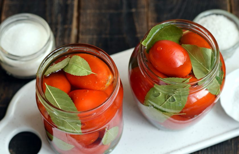 1. Этап. Помидоры с вишневыми листьями на зиму: Параллельно вскипятите воду. Кипятком залейте содержимое тары по самое горлышко, прикройте крышкой, дайте постоять 10 минут.