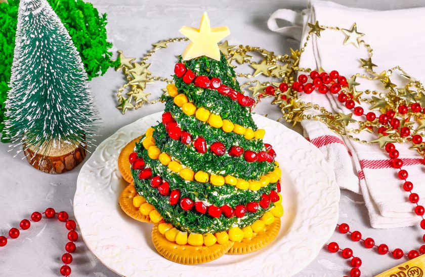 1. Этап. Сырная ёлочка: На тарелку выложите кругом крекеры, на них - зеленую ёлку из творога. Аккуратно украсьте ее гирляндами из зерен граната и кукурузы. Сверху разместите звездочку из сыра или помидор черри небольшого размера. Подайте закуску к столу.