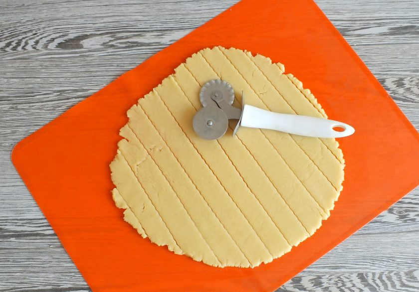 1. Этап. Пирог с творогом и сгущенкой: Малую часть теста раскатайте в пласт толщиной 0,5 см. Нарежьте полосы, шириной 3,5 см.