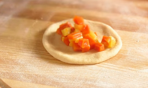 1. Этап. Пирожки с яблоками и тыквой в духовке: 7. Тесто нужно обмять и разделить на одинаковые шарики. Каждый раскатайте скалкой в лепешку. Выложите столовую ложку начинки, соберите края теста, вытяните пирожок нужной формы и соедините края.