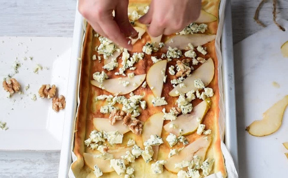 1. Этап. Пицца с грушами и сыром: 4. Противень поставьте на стол, сбрызните тесто водой, разложите ломтики груш и сыра (горгонзола, с плесенью или острый), посыпьте начинку дроблеными орехами.