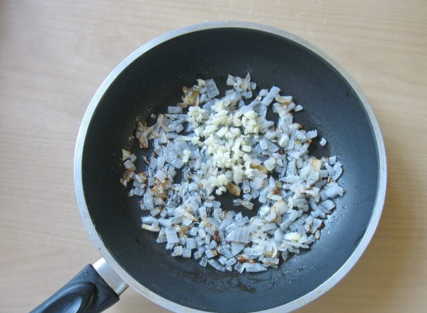 1. Этап. Баклажаны с фаршем в духовке: Поджарьте лук до прозрачности и добавьте измельченный чеснок.